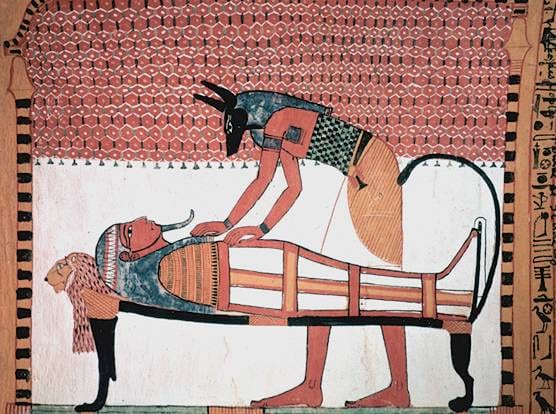 Peinture égyptienne montrant un dieu à tête de chacal penché sur une momie allongée