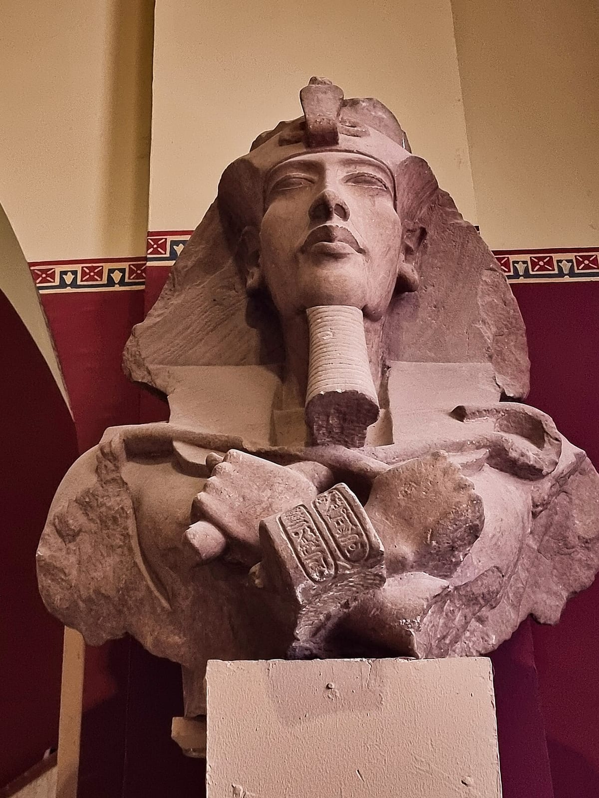 Statue colossale d'un pharaon au visage allongé, bras croisés sur la poitrine