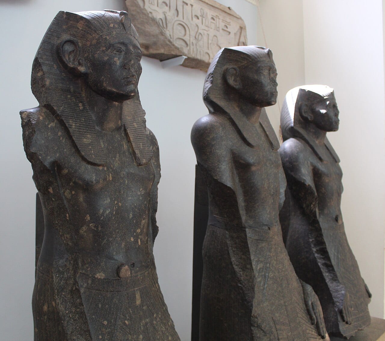 Trois statues de granit noir représentant le même pharaon