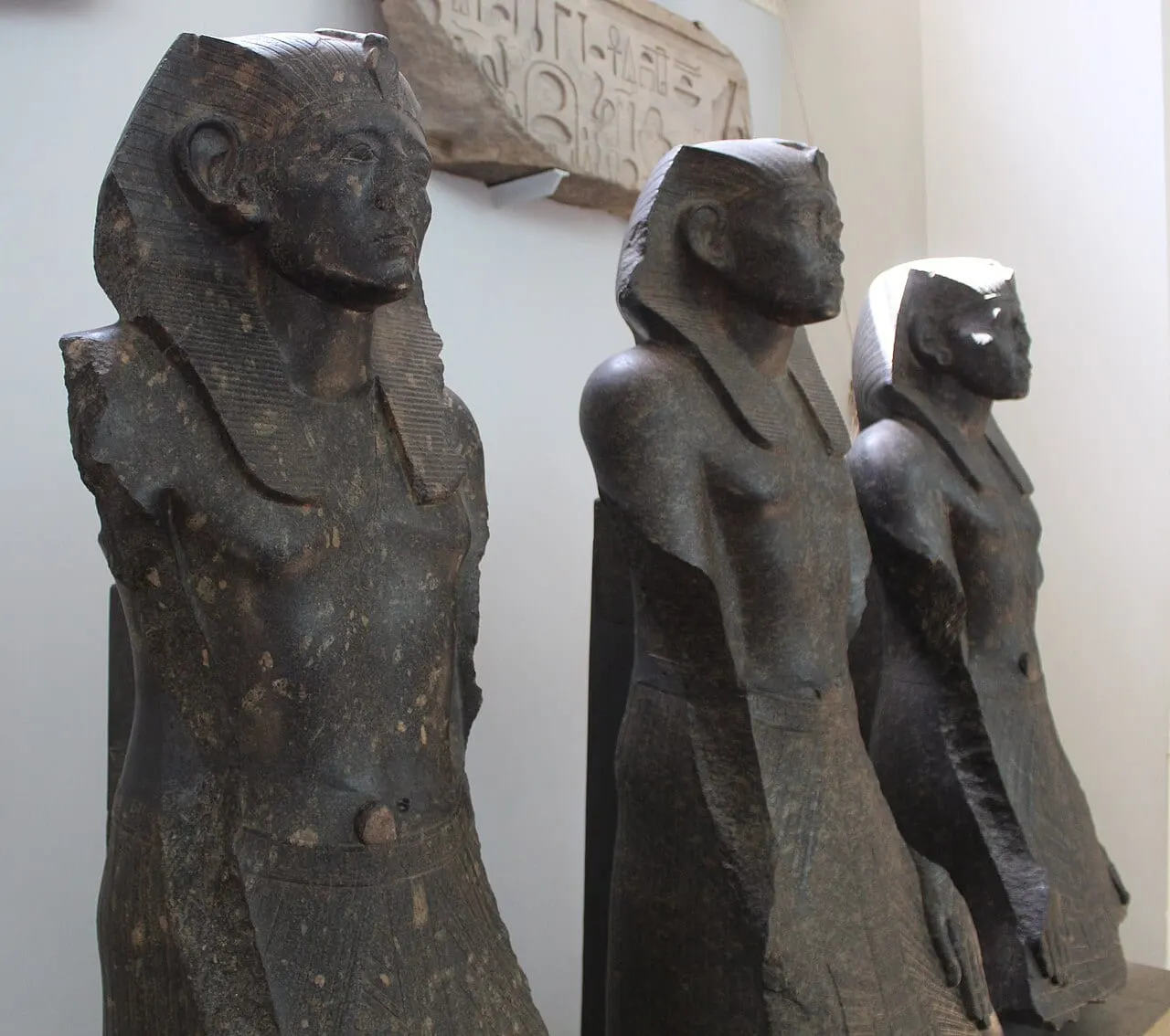 Trois statues de granit noir représentant le même pharaon
