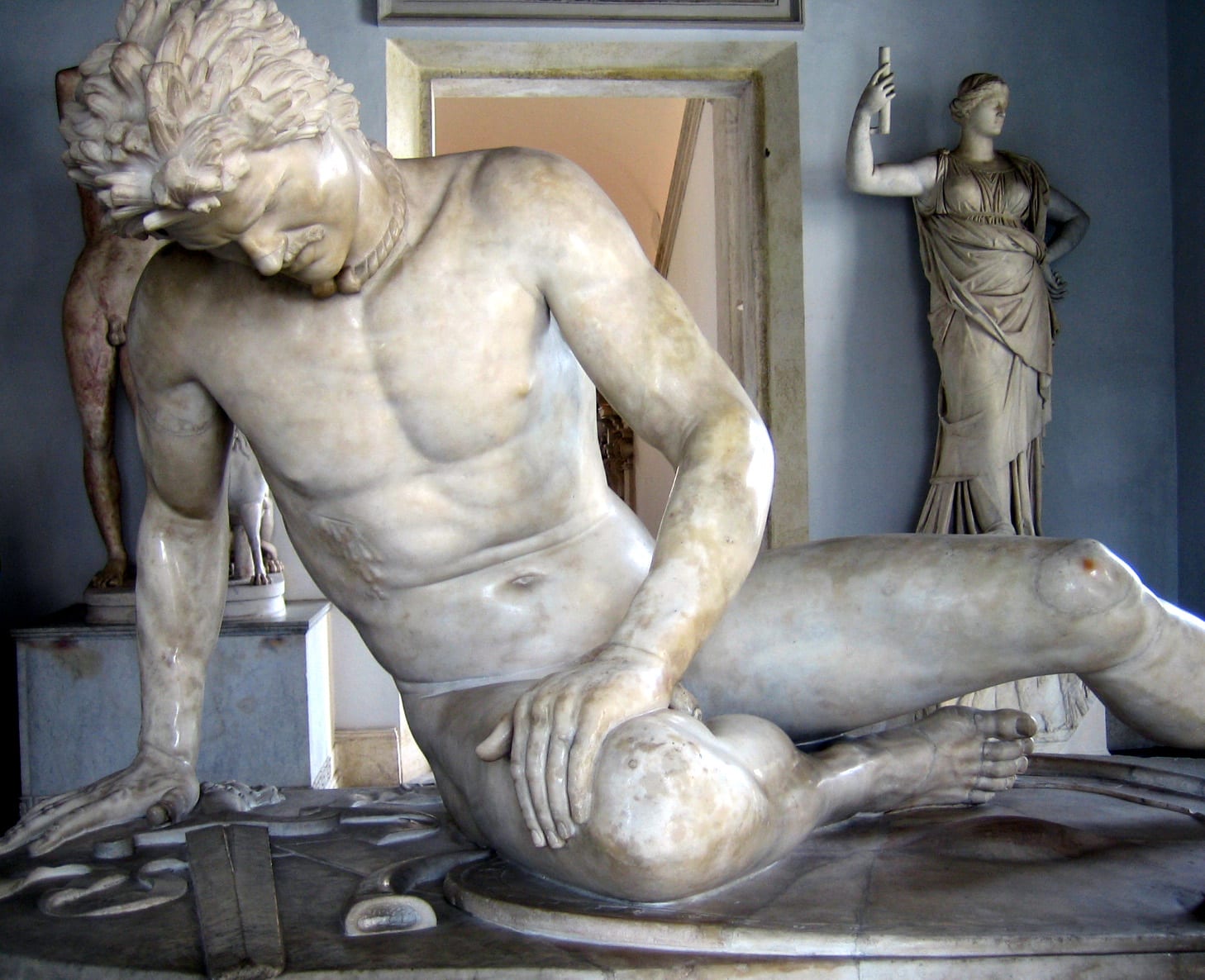 Statue de marbre d'un guerrier nu blessé, effondré sur son bouclier