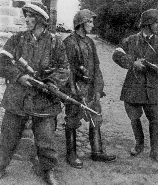 Trois jeunes résistants polonais casqués et armés dans une rue