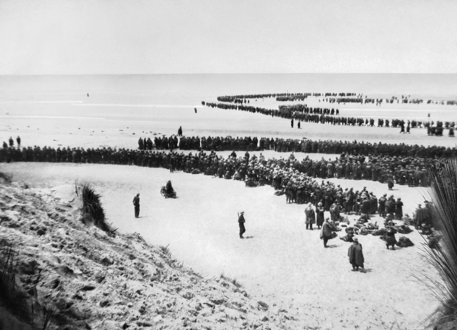 Longues files de soldats sur une plage, attendant d'embarquer