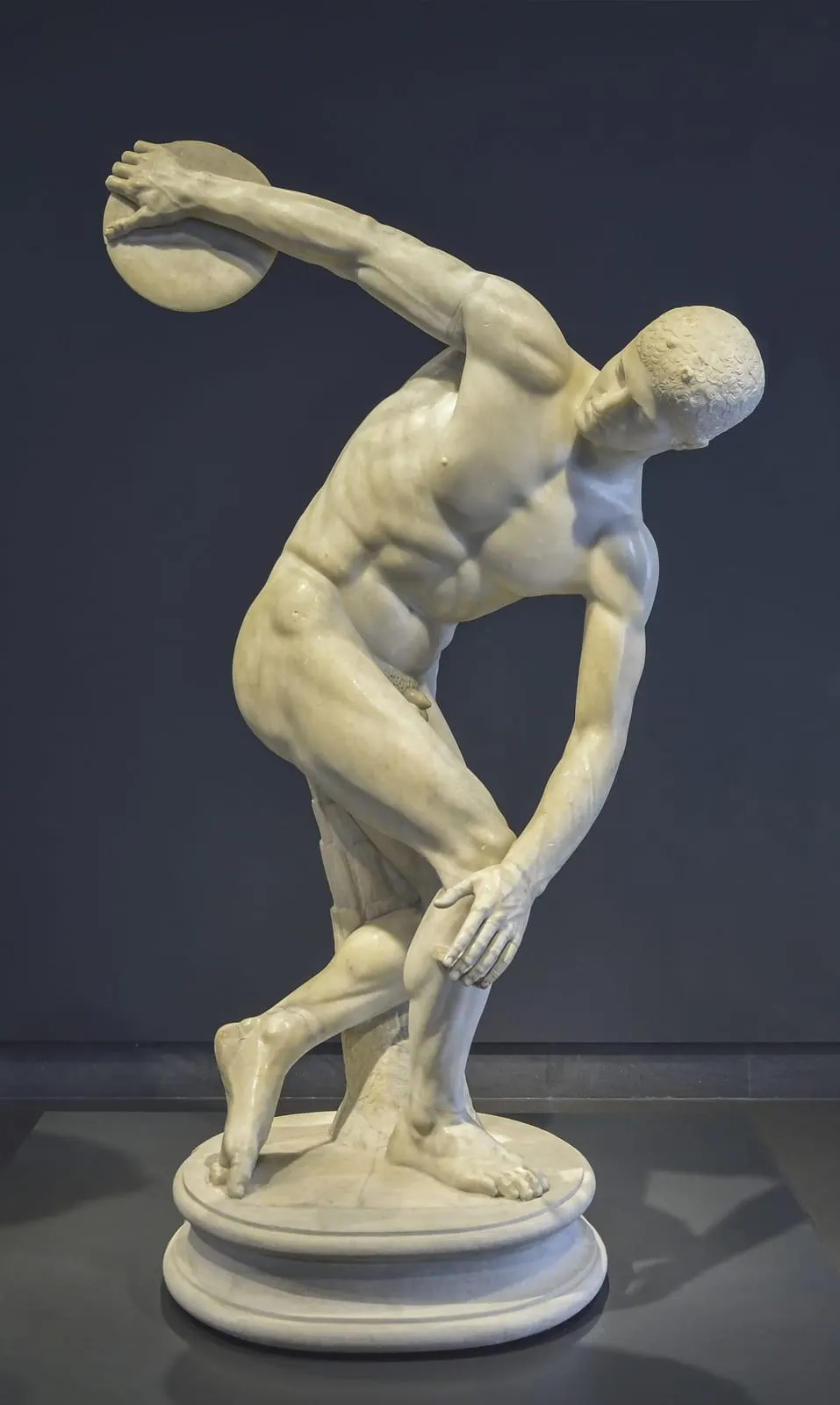 Statue de marbre d'un athlète nu ramassé sur lui-même, prêt à lancer le disque