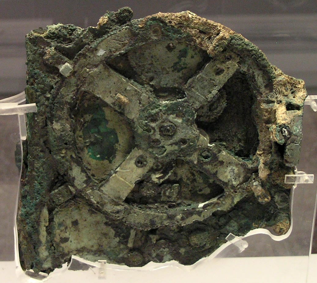 Fragment corrodé d'un mécanisme antique en bronze laissant voir des roues dentées