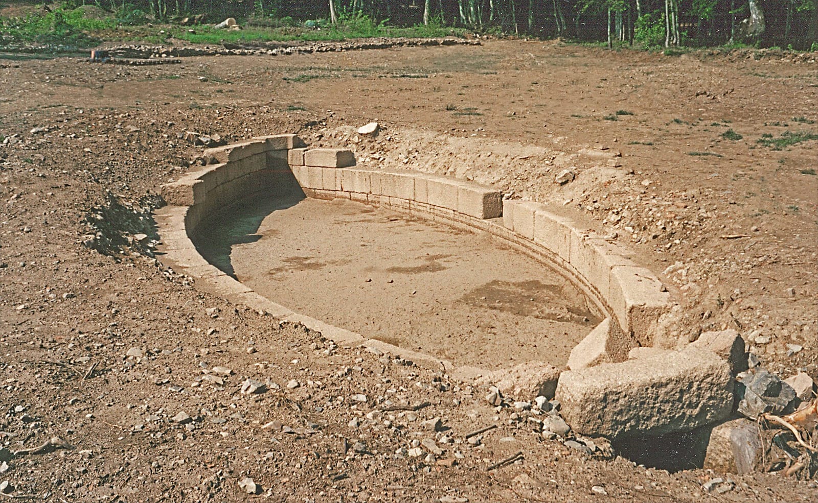 Archéologues au travail autour d'un grand bassin de pierre dégagé du sol