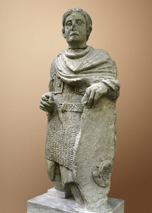 Statue de pierre d'un guerrier gaulois en cotte de mailles, portant un torque et un bouclier