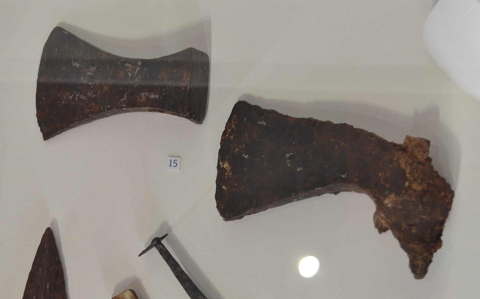 Deux fers de hache corrodés et une pointe de lance en fer, exposés en vitrine
