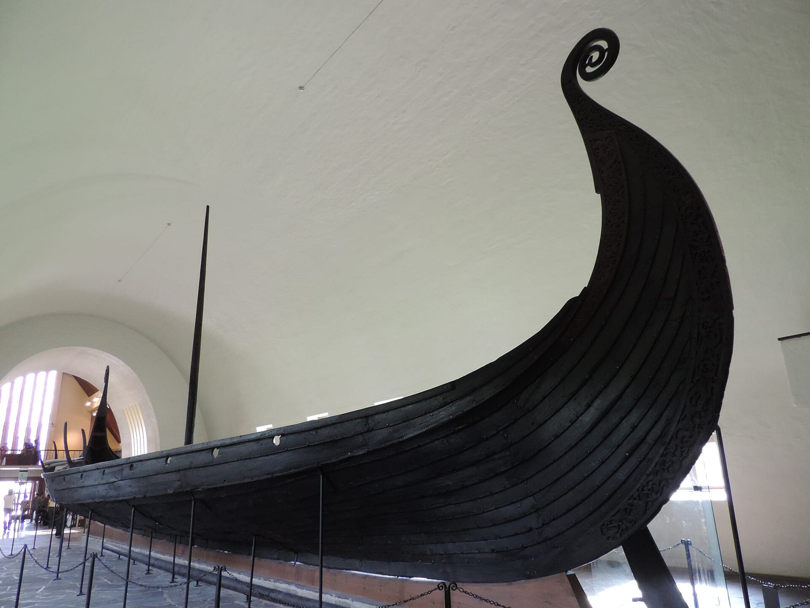 Proue élancée et enroulée en spirale d'un navire en bois sombre, dans un musée