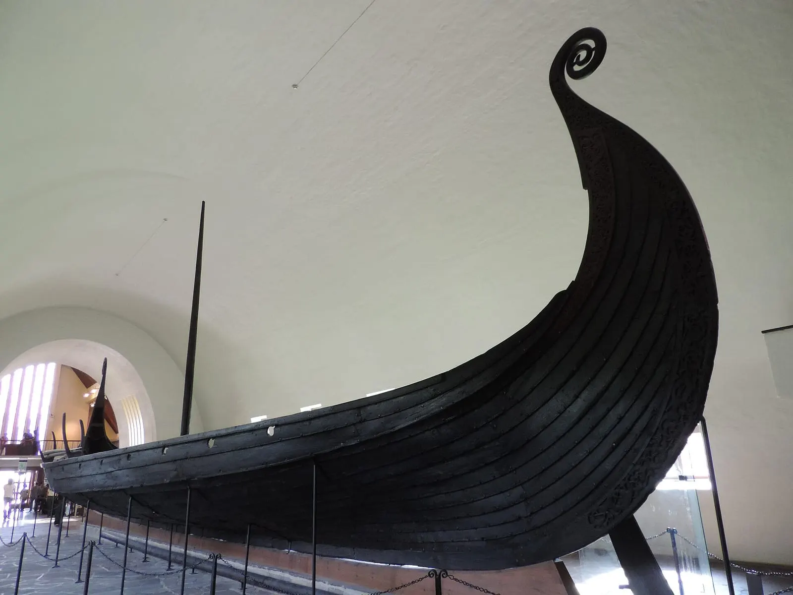 Proue élancée et enroulée en spirale d'un navire en bois sombre, dans un musée